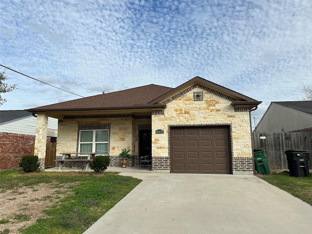 view of front of house with fence, an attached garage, driveway, and stone siding