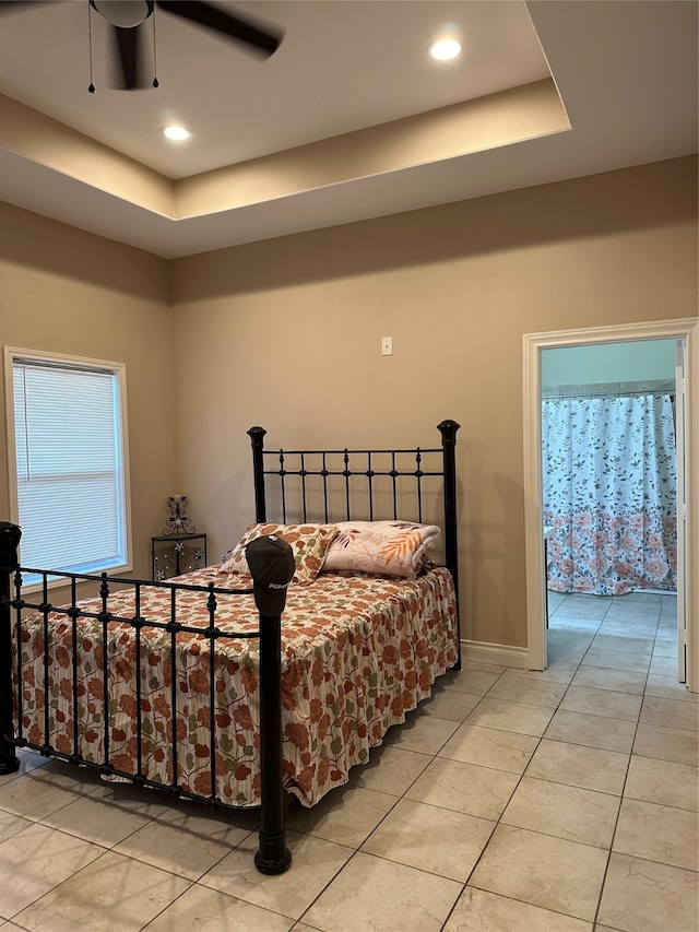 bedroom with ceiling fan, access to exterior, a tray ceiling, and light tile patterned floors