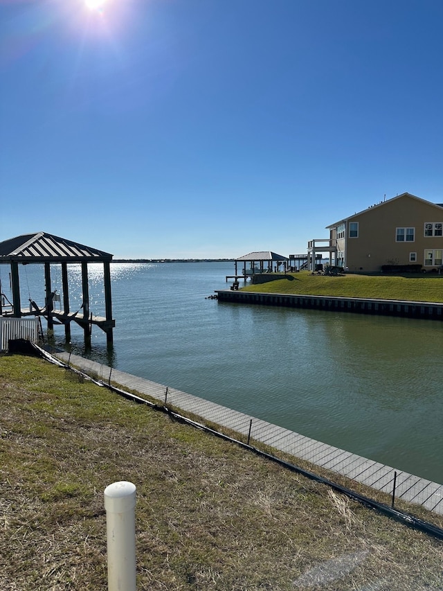 view of dock with a water view and a yard