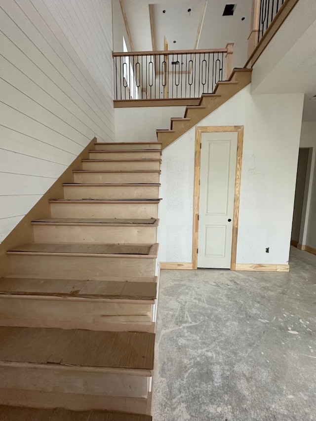 stairway with concrete flooring and a high ceiling