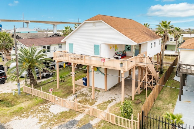 back of property with a fenced front yard, roof with shingles, dirt driveway, an attached garage, and a residential view