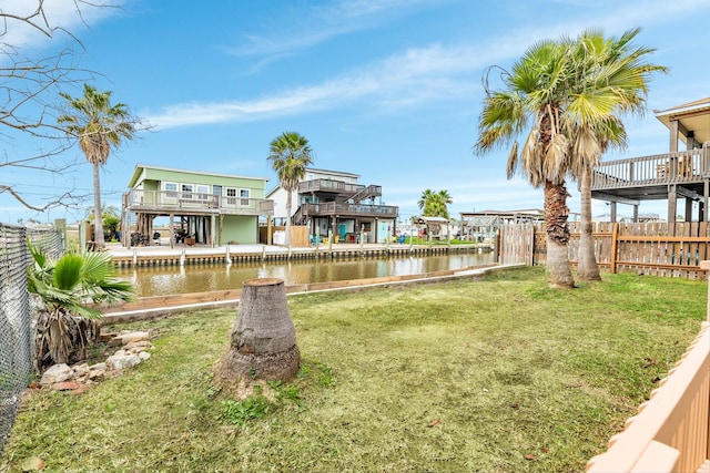 rear view of property featuring a water view, fence, and a yard