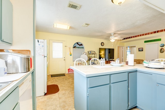 kitchen featuring light tile patterned flooring, white appliances, a textured ceiling, ceiling fan, and blue cabinetry