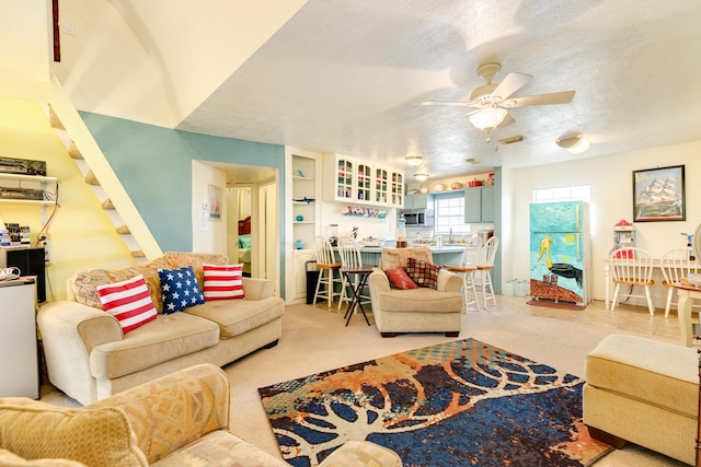 living room featuring carpet, visible vents, ceiling fan, and a textured ceiling