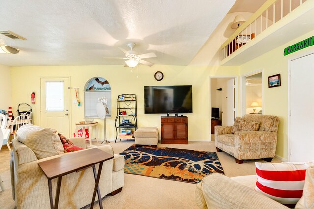 carpeted living room with a textured ceiling and ceiling fan