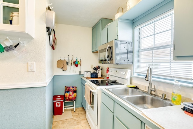 kitchen with light tile patterned floors, electric range, a sink, light countertops, and stainless steel microwave