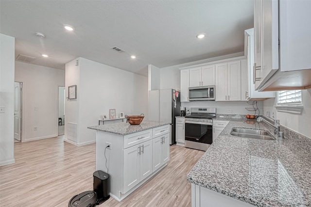 kitchen featuring white cabinets, stainless steel appliances, sink, and a kitchen island