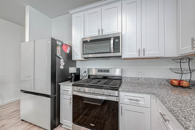 kitchen with light stone counters, stainless steel appliances, light wood-type flooring, and white cabinetry