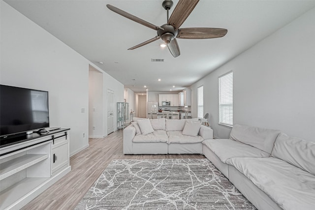 living room with light hardwood / wood-style floors and ceiling fan