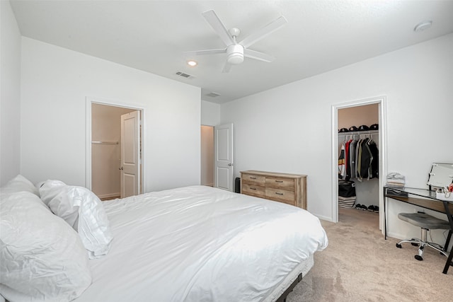 carpeted bedroom with ceiling fan, a closet, and a spacious closet