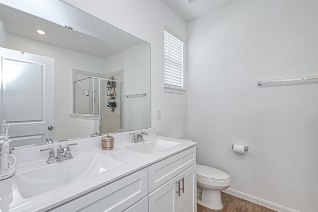 bathroom featuring hardwood / wood-style floors, vanity, a shower with shower door, and toilet