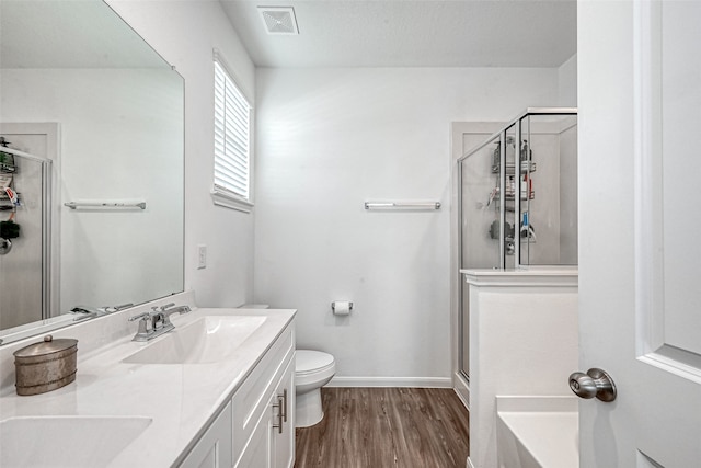 bathroom featuring walk in shower, vanity, toilet, and wood-type flooring