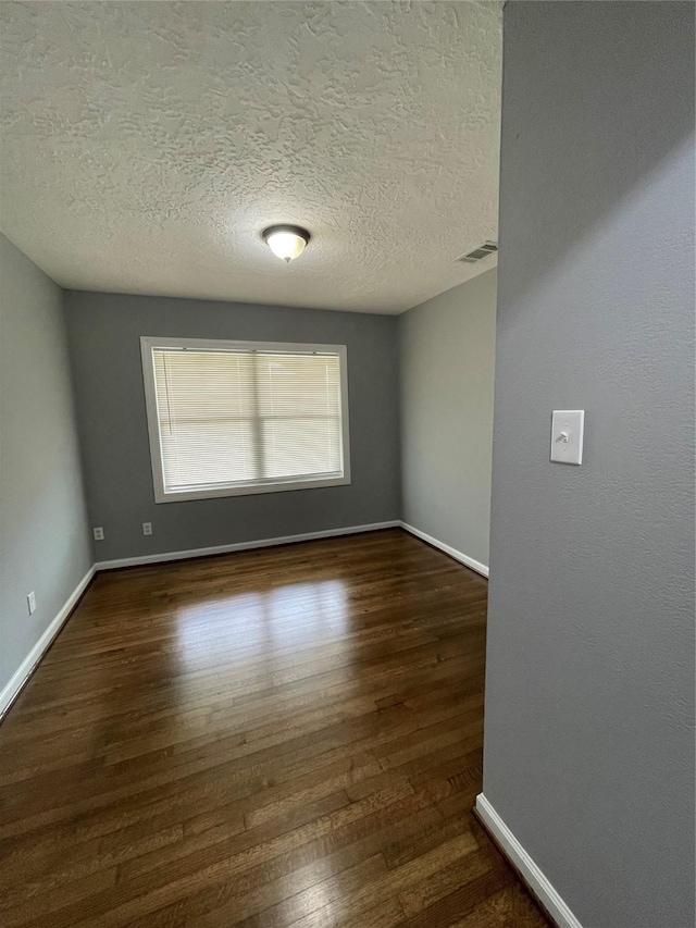 spare room with dark wood-type flooring and a textured ceiling