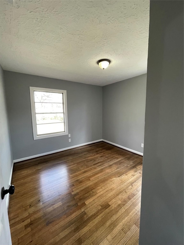 spare room featuring hardwood / wood-style floors and a textured ceiling