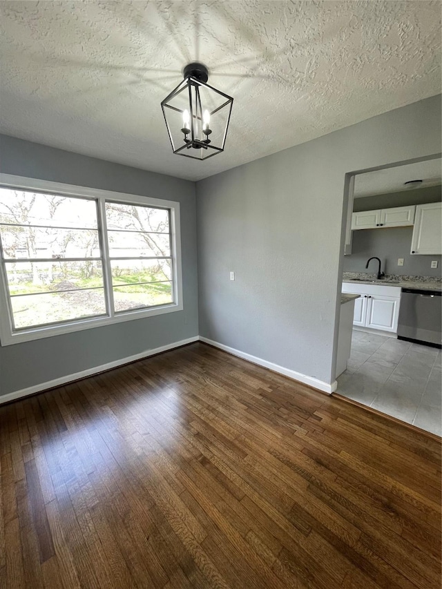 unfurnished dining area featuring light wood-type flooring, a textured ceiling, and a notable chandelier