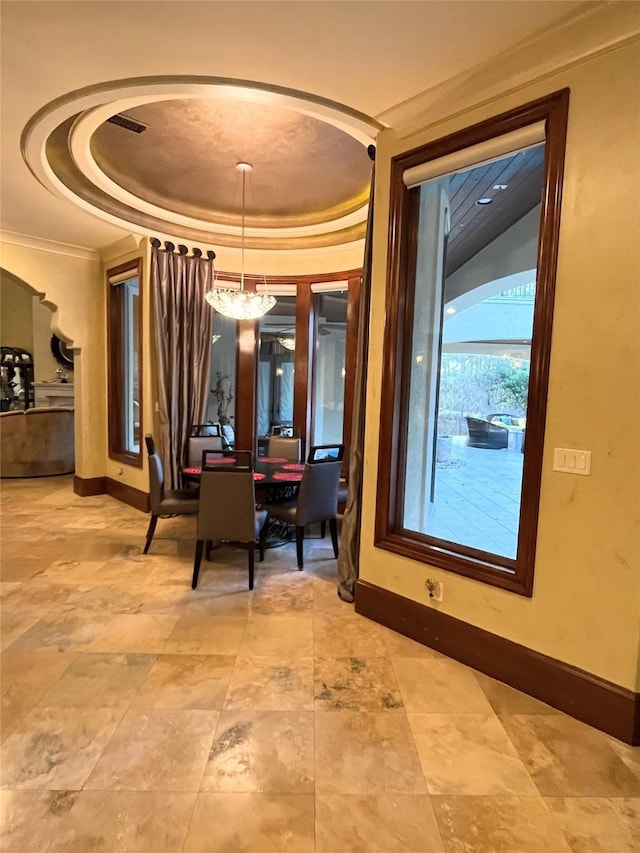 dining area with a tray ceiling, ornamental molding, and a notable chandelier