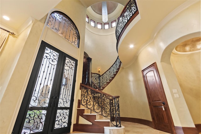 entrance foyer featuring hardwood / wood-style floors, a towering ceiling, and french doors