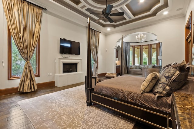 bedroom featuring coffered ceiling, ceiling fan with notable chandelier, crown molding, hardwood / wood-style flooring, and a fireplace