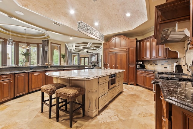 kitchen with tasteful backsplash, crown molding, dark stone counters, a breakfast bar area, and a kitchen island