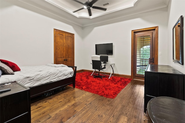 bedroom with wood-type flooring, a raised ceiling, ceiling fan, and ornamental molding