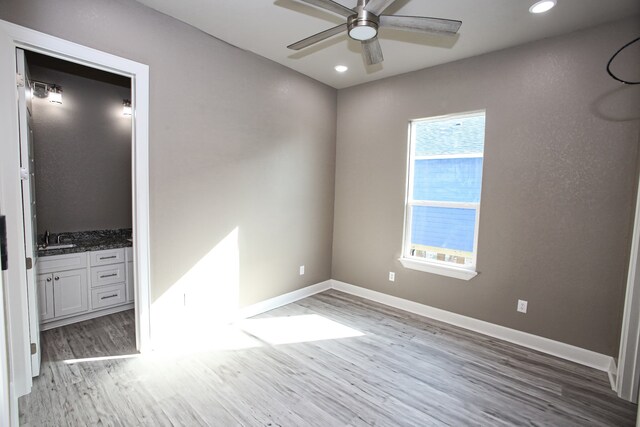 empty room with sink, ceiling fan, and hardwood / wood-style flooring