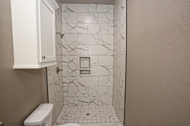 bathroom featuring a tile shower and toilet