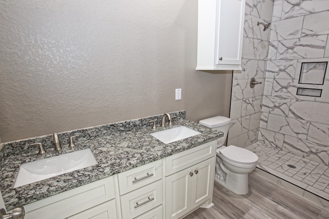 bathroom featuring tiled shower, hardwood / wood-style flooring, vanity, and toilet