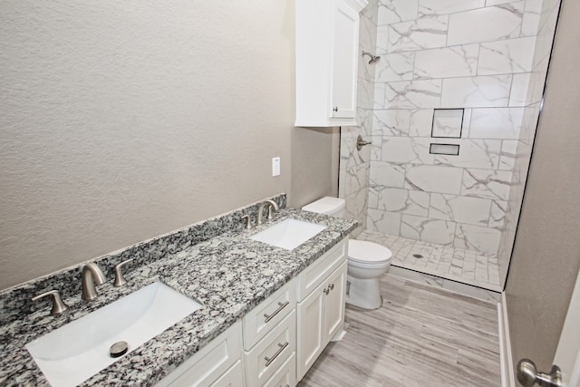 bathroom featuring vanity, hardwood / wood-style floors, toilet, and tiled shower