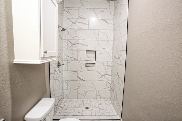 bathroom featuring a tile shower and toilet