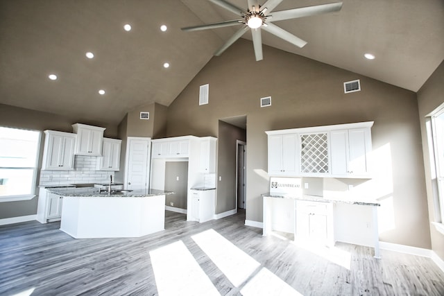 kitchen featuring high vaulted ceiling, white cabinets, ceiling fan, and stone counters