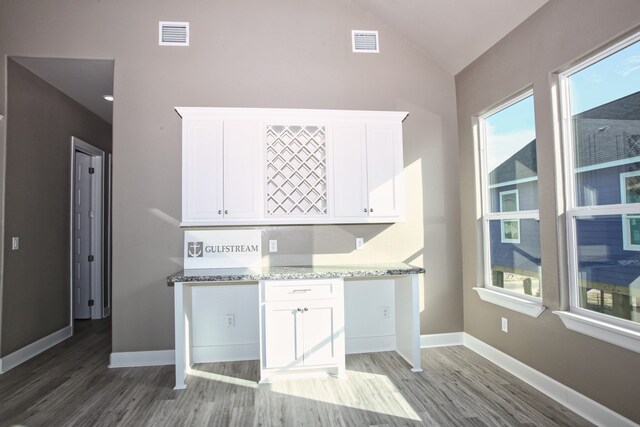 kitchen with wood-type flooring, white cabinets, and lofted ceiling