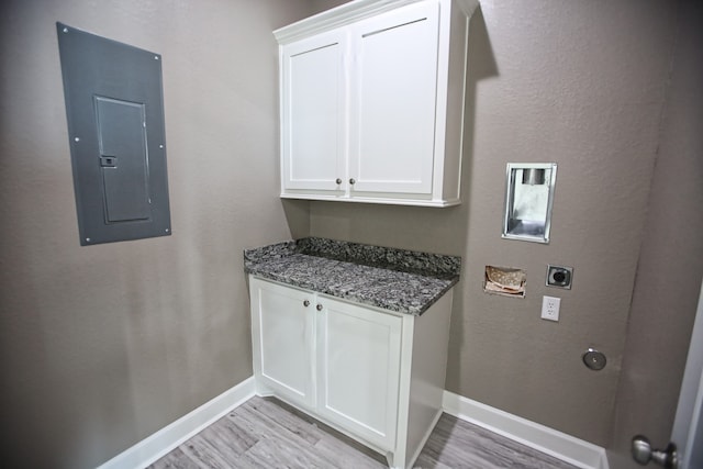 laundry room featuring cabinets, electric panel, light hardwood / wood-style flooring, and hookup for an electric dryer