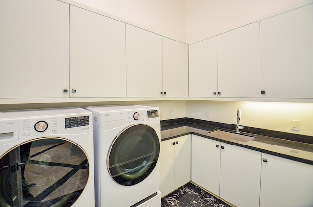 clothes washing area featuring washer and clothes dryer, tile floors, cabinets, and sink