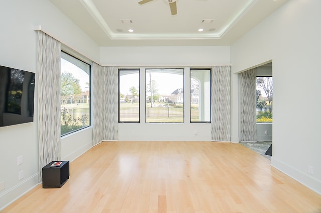 empty room featuring a tray ceiling, light hardwood / wood-style floors, and ceiling fan