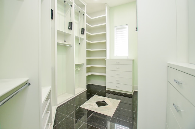 walk in closet featuring dark tile flooring