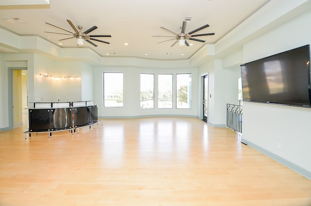 living room featuring a tray ceiling, ceiling fan, and light wood-type flooring