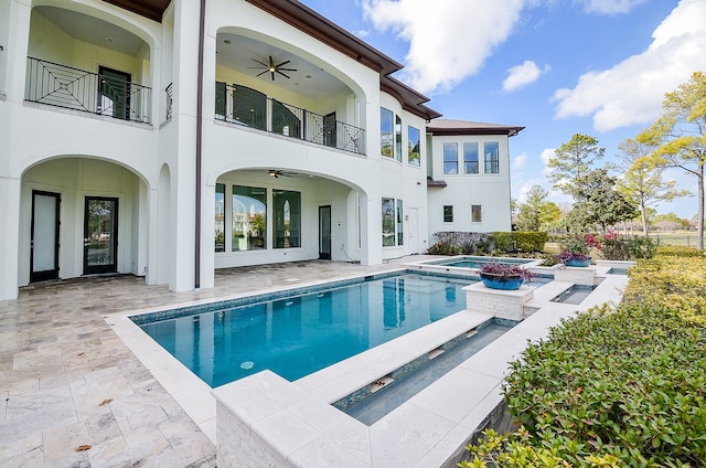 back of house with a balcony, a pool with hot tub, ceiling fan, and a patio area