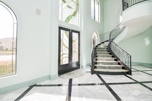 entrance foyer with a high ceiling, light tile floors, and french doors