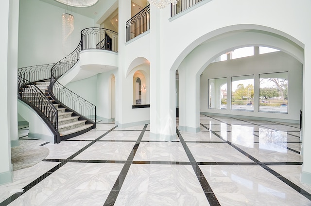 foyer entrance with light tile floors and a towering ceiling