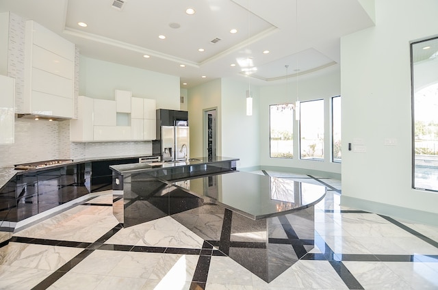 kitchen featuring light tile floors, a center island with sink, white cabinetry, and a raised ceiling