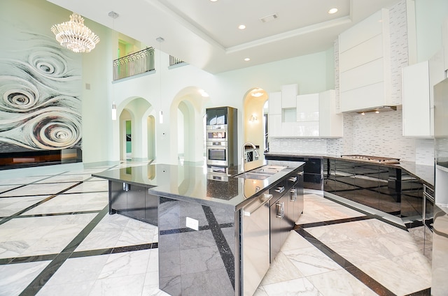 kitchen featuring a chandelier, light tile floors, a kitchen island with sink, and white cabinetry