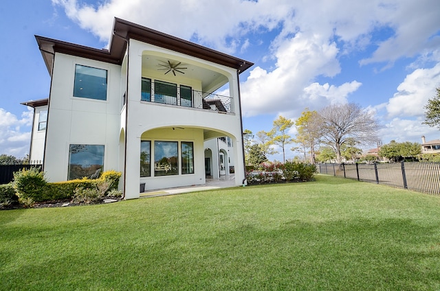 rear view of house featuring a yard, a balcony, ceiling fan, and a patio