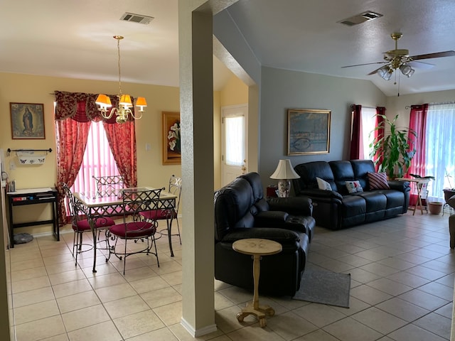 tiled living room featuring a healthy amount of sunlight and ceiling fan with notable chandelier