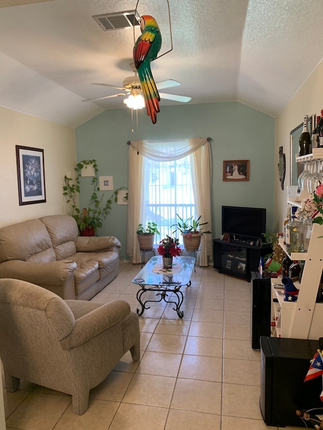 living room featuring lofted ceiling, a textured ceiling, ceiling fan, and light tile flooring