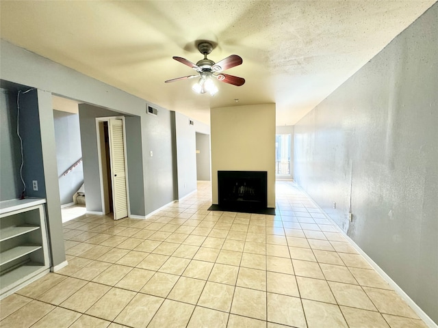 unfurnished living room featuring a textured ceiling, ceiling fan, and light tile floors