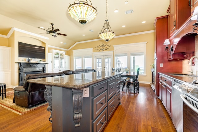 kitchen with sink, ceiling fan, dark hardwood / wood-style flooring, a kitchen bar, and a center island