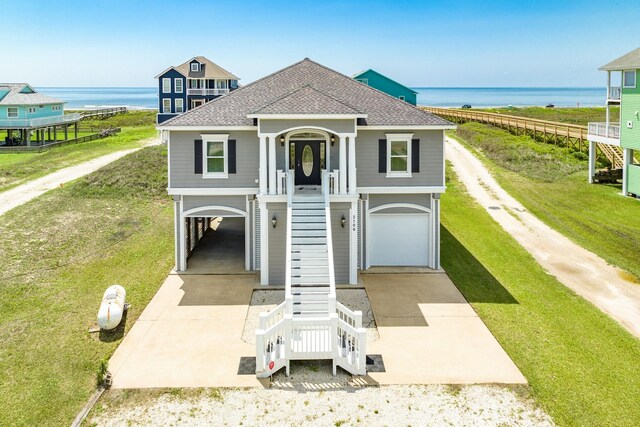 coastal home with a water view, a front lawn, and a garage