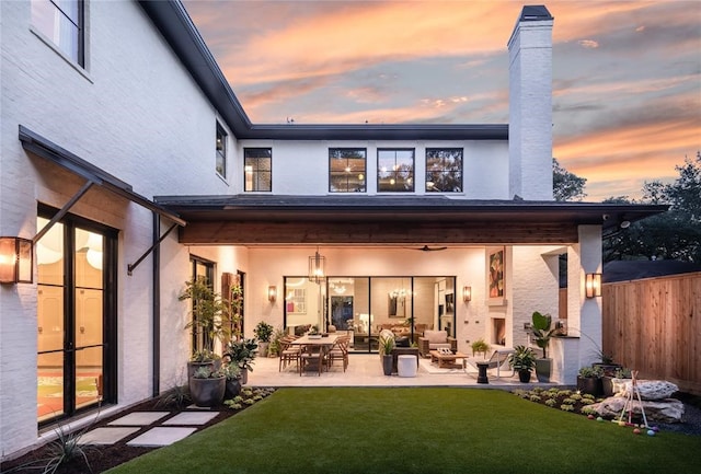 back house at dusk with a patio area and a yard