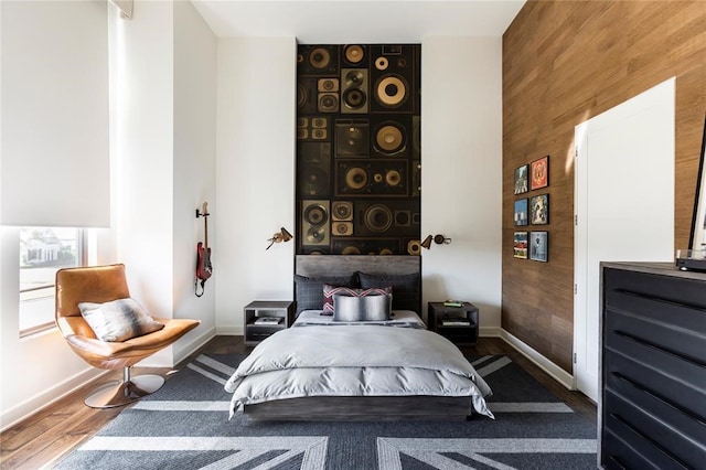 bedroom with wood walls and dark hardwood / wood-style flooring