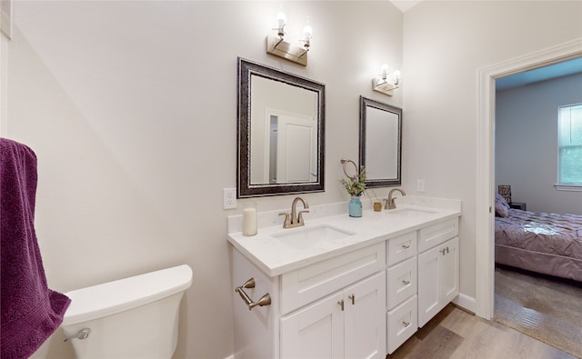 bathroom with toilet, hardwood / wood-style flooring, and dual bowl vanity